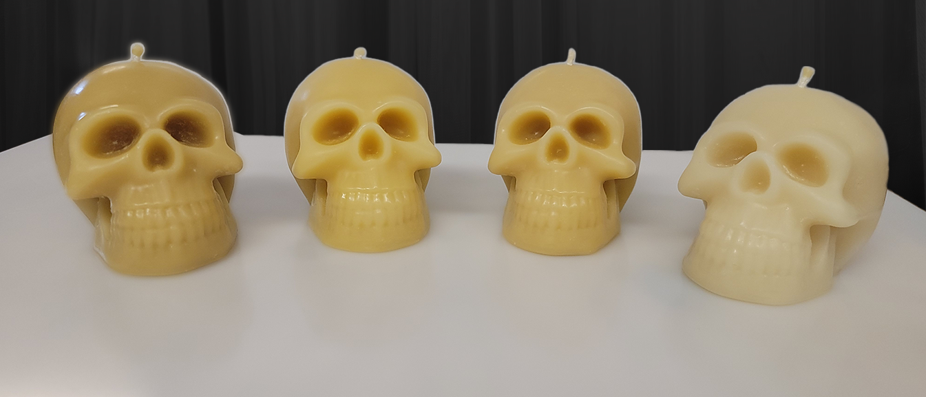 Four beeswax skull candles showing a range of natural shades from dark yellow to ivory